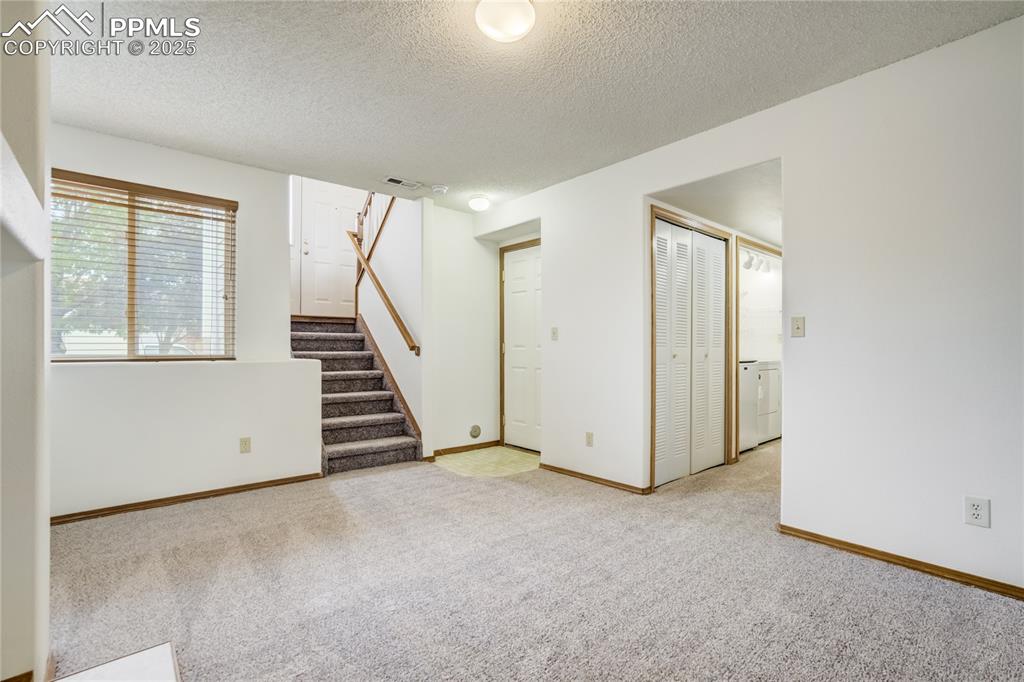 Image 21 of 34: Spare room featuring light colored carpet, stairway, a textured ceiling, an