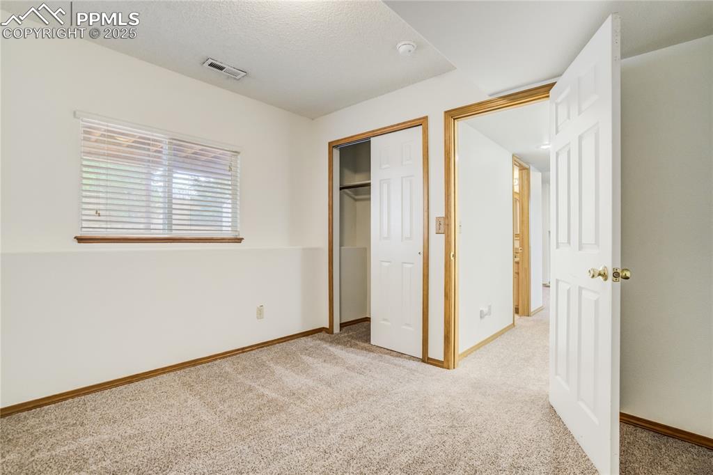 Image 23 of 34: Unfurnished bedroom featuring light carpet, a closet, and a textured ceilin