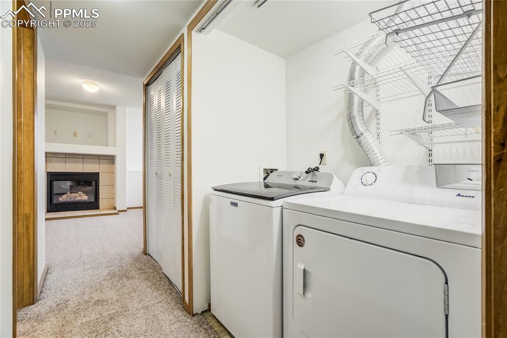 Image 26 of 34: Laundry area featuring light colored carpet, a fireplace, and independent w