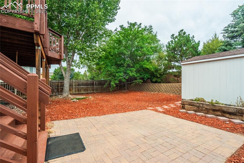 Image 27 of 34: Fenced backyard with a patio area, stairway, and a wooden deck