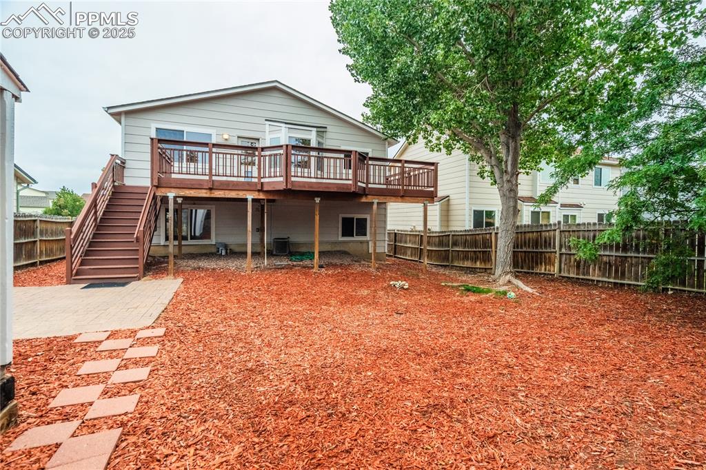 Image 29 of 34: Rear view of house with a fenced backyard, a wooden deck, and stairs
