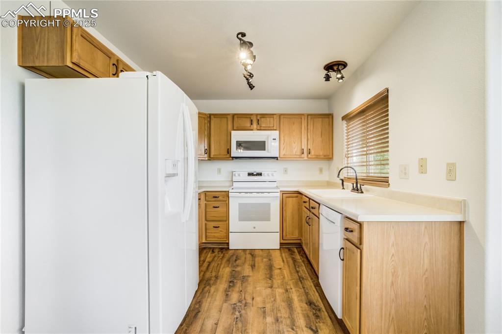 Image 5 of 34: Kitchen featuring white appliances, light countertops, dark wood-style floo
