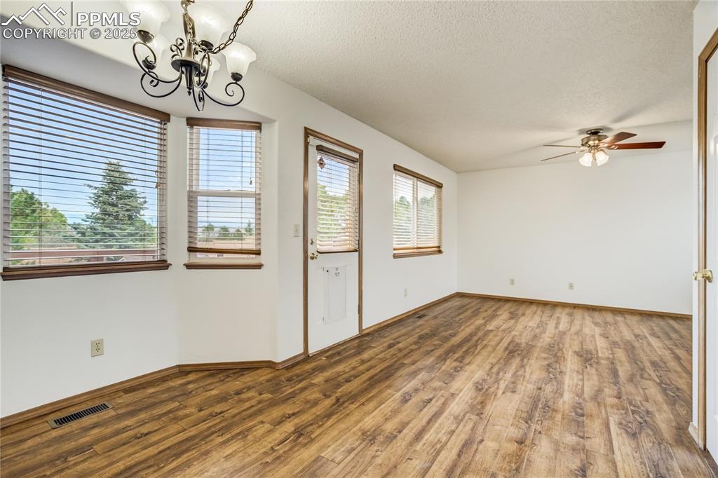Image 8 of 34: Spare room with a chandelier, wood finished floors, a textured ceiling, and