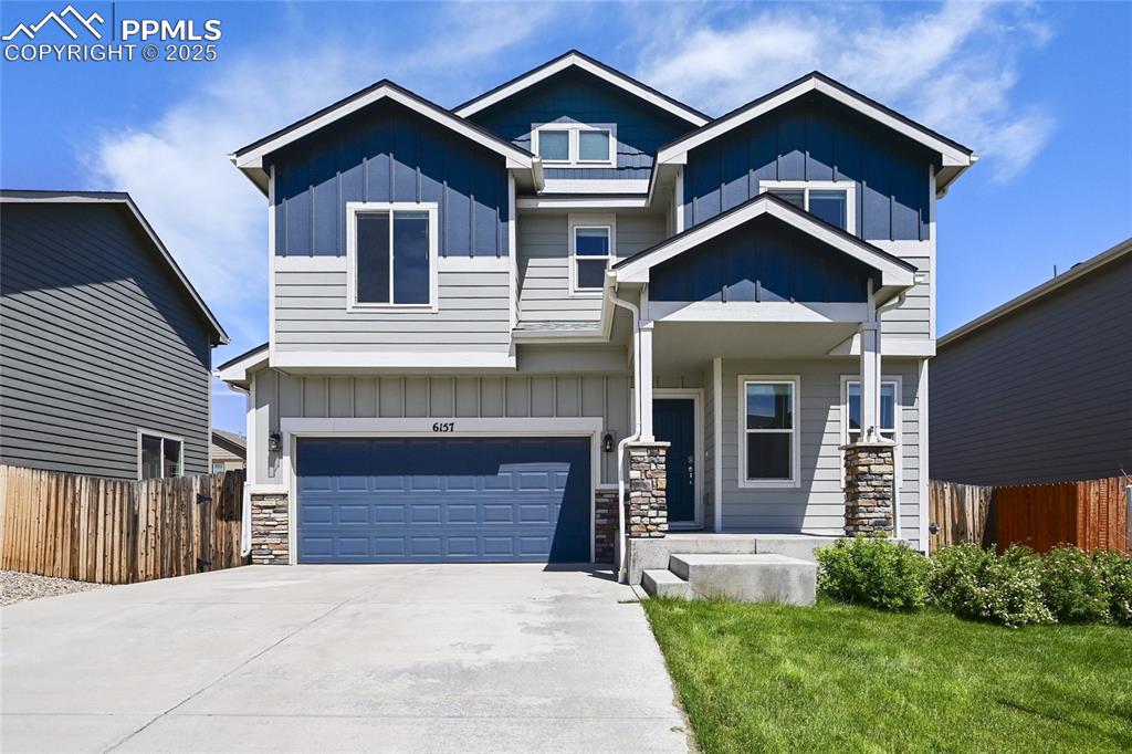 Caption: Craftsman inspired home featuring a garage, concrete driveway, stone siding, and board and batten si