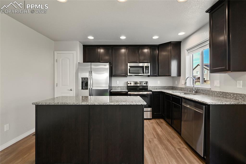 Image 11 of 29: Kitchen with appliances with stainless steel finishes, light wood-style flo