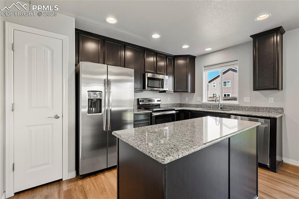 Image 12 of 29: Kitchen featuring stainless steel appliances, light stone countertops, ligh
