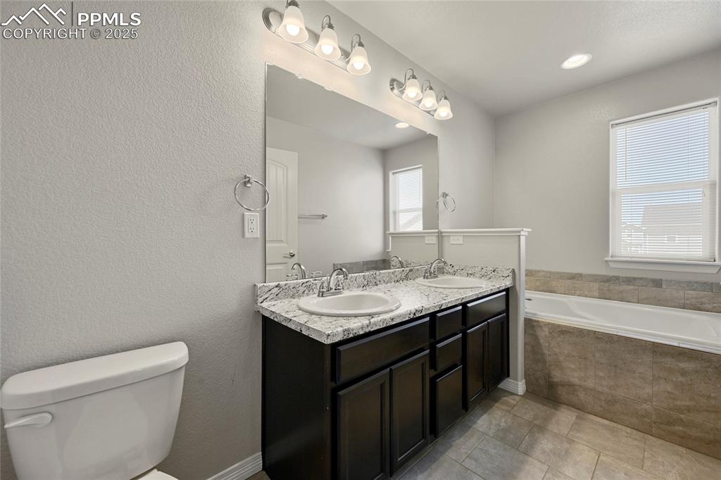 Image 18 of 29: Bathroom with a bath, double vanity, and tile patterned floors