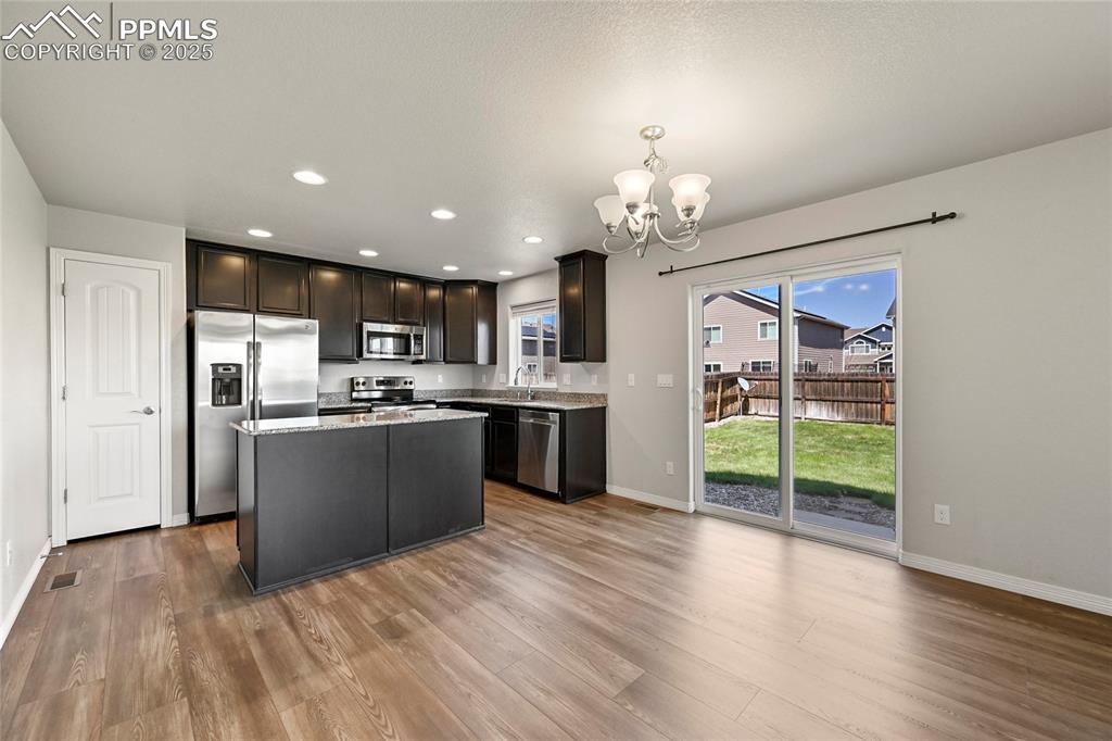 Image 9 of 29: Kitchen featuring stainless steel appliances, a chandelier, wood finished f