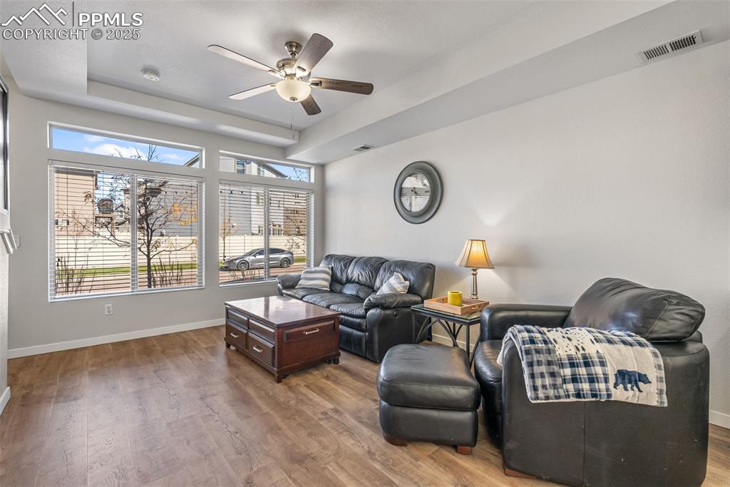 Image 10 of 50: Living room with dark wood-style flooring, a ceiling fan, and a raised ceil