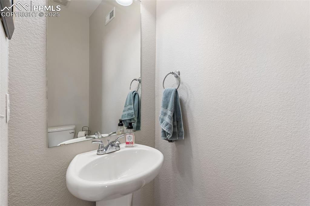 Image 15 of 50: Half bathroom with a textured wall and a sink