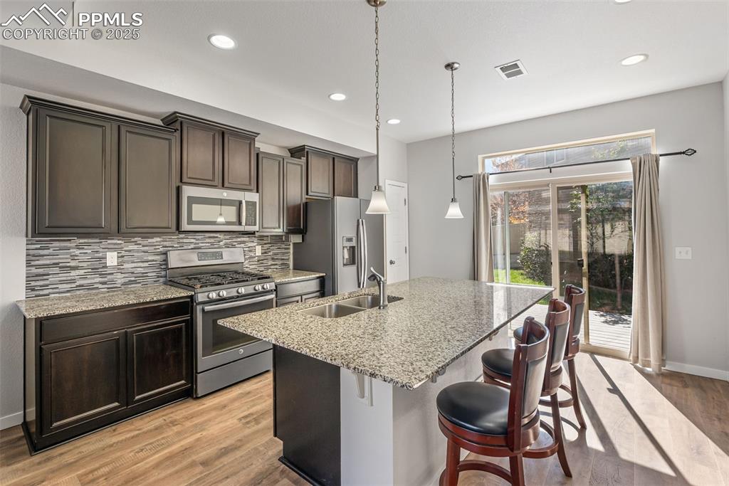 Image 2 of 50: Kitchen featuring stainless steel appliances, dark brown cabinets, a kitche