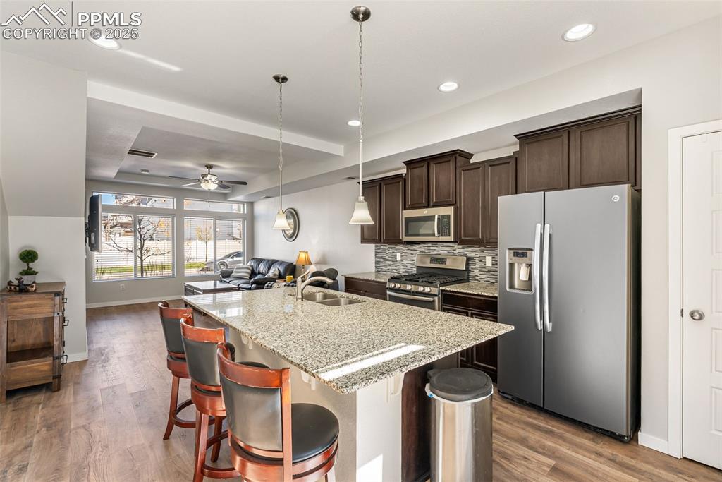 Image 3 of 50: Kitchen with stainless steel appliances, dark brown cabinetry, hanging ligh