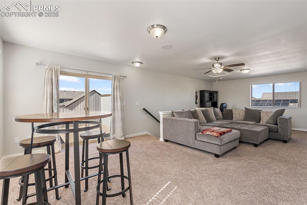 Image 35 of 50: Living room with light colored carpet and a ceiling fan