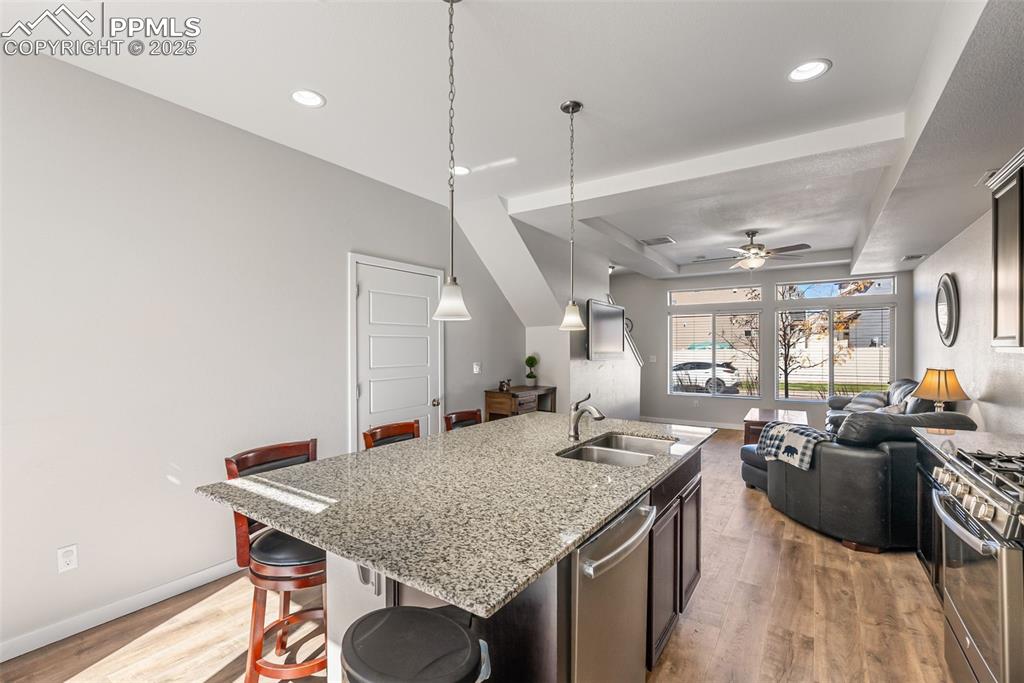 Image 4 of 50: Kitchen featuring a kitchen breakfast bar, light wood-style floors, a tray