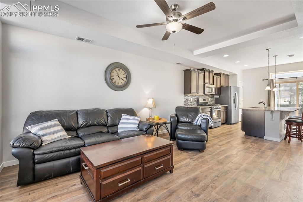 Image 9 of 50: Living area with light wood-style flooring, ceiling fan, and recessed light