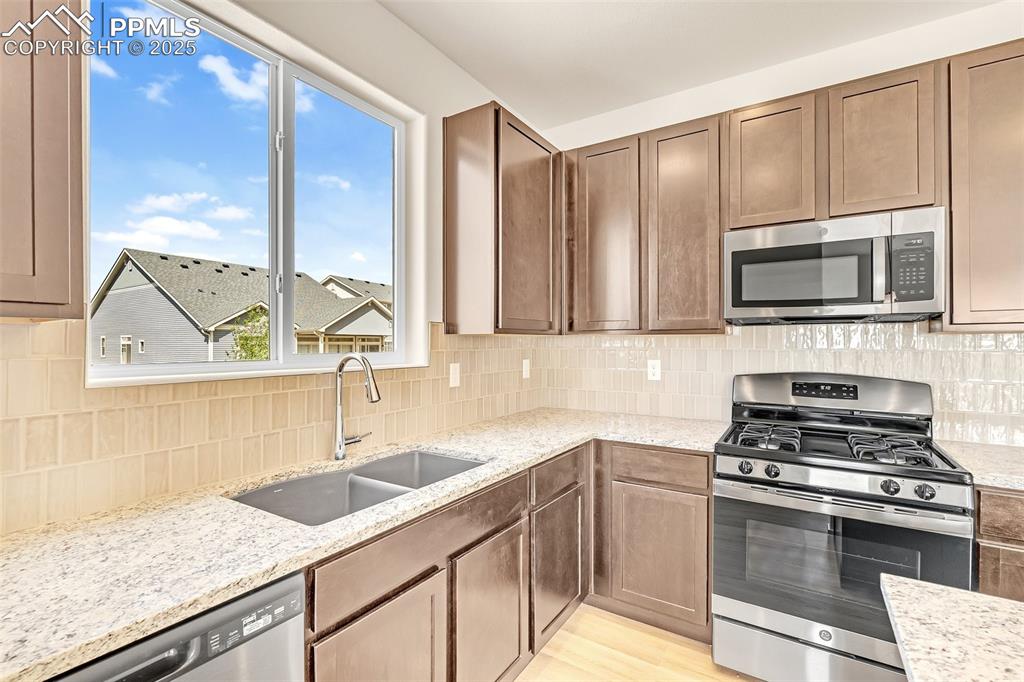 Image 13 of 39: Kitchen with appliances with stainless steel finishes, tasteful backsplash,