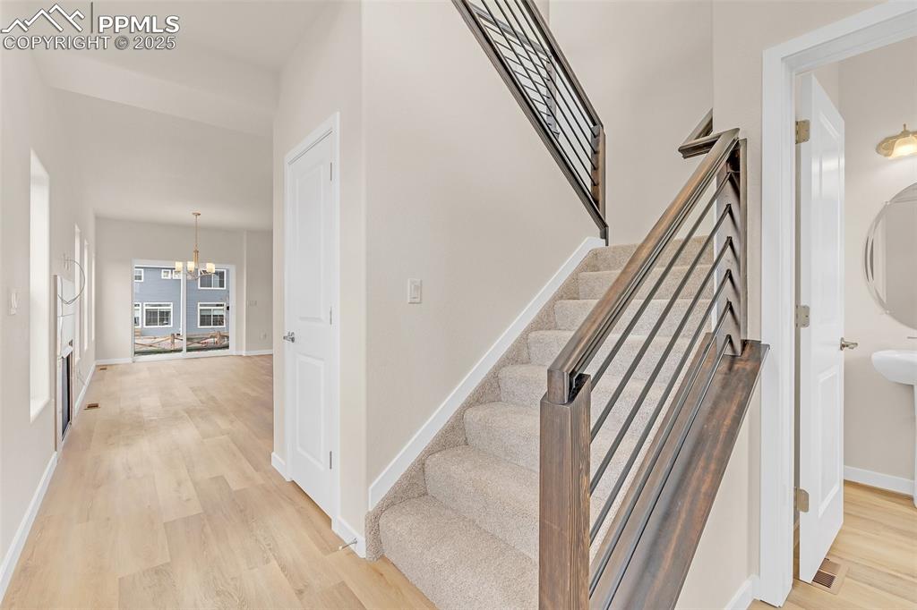 Image 14 of 39: Staircase with a chandelier and wood finished floors
