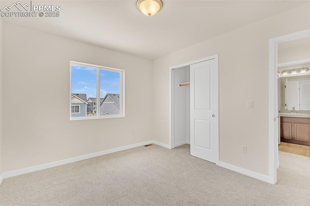 Image 18 of 39: Unfurnished bedroom featuring light carpet, a closet, and ensuite bath