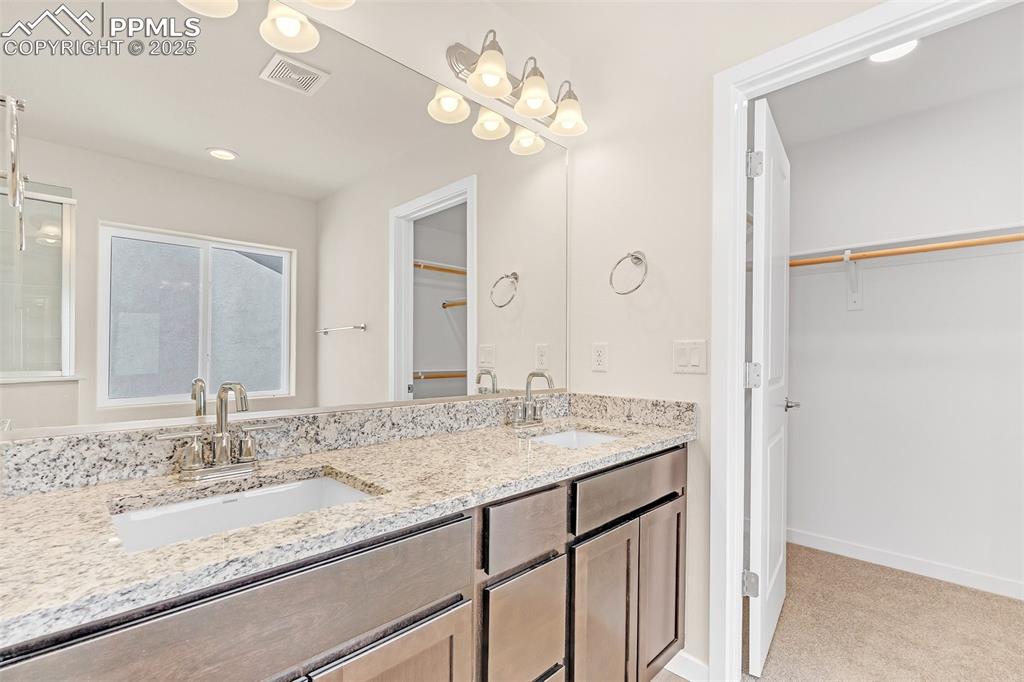 Image 28 of 39: Bathroom featuring a spacious closet, double vanity, recessed lighting, and