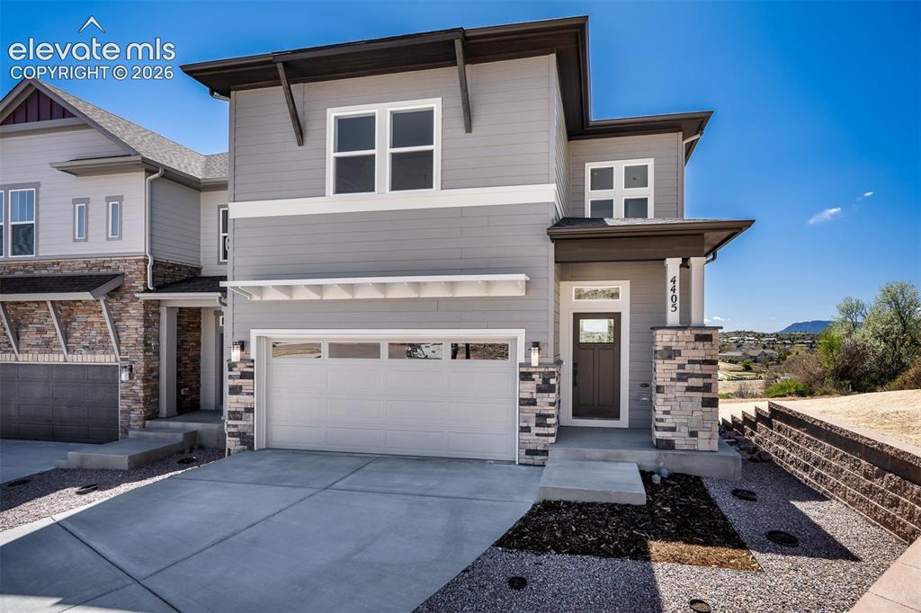 Caption: Contemporary multi-level exterior featuring gray siding with white trim accents, a stone veneer acce