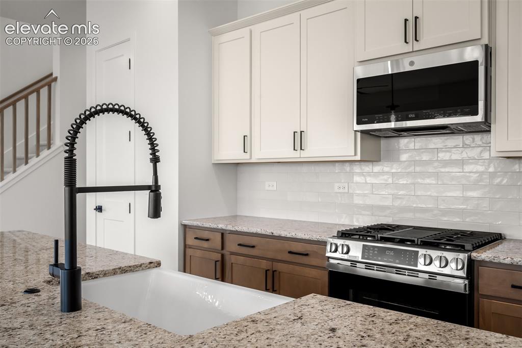Image 11 of 45: Kitchen featuring a white farmhouse sink with a matte black pull-down fauce