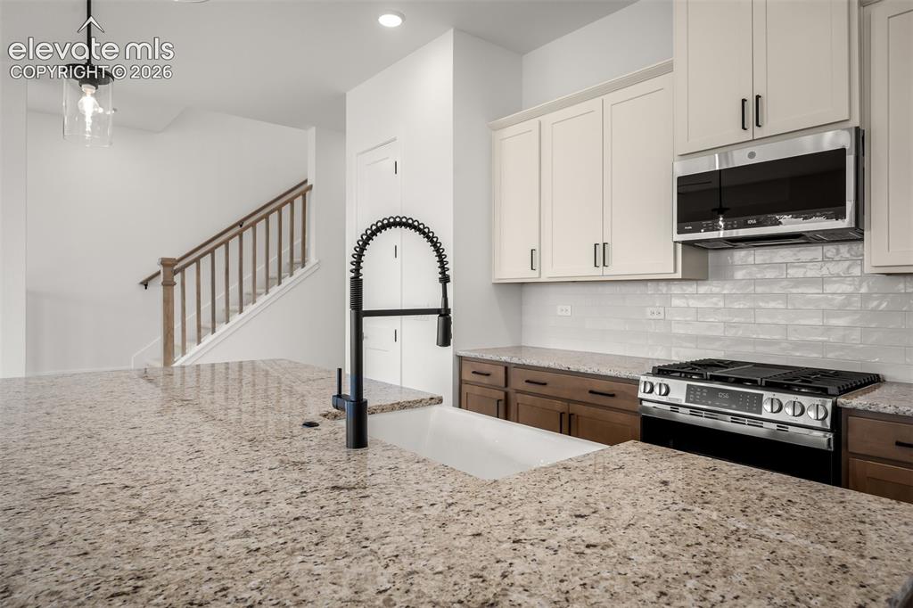 Image 13 of 45: Kitchen featuring granite countertops, a white farmhouse sink with a matte 