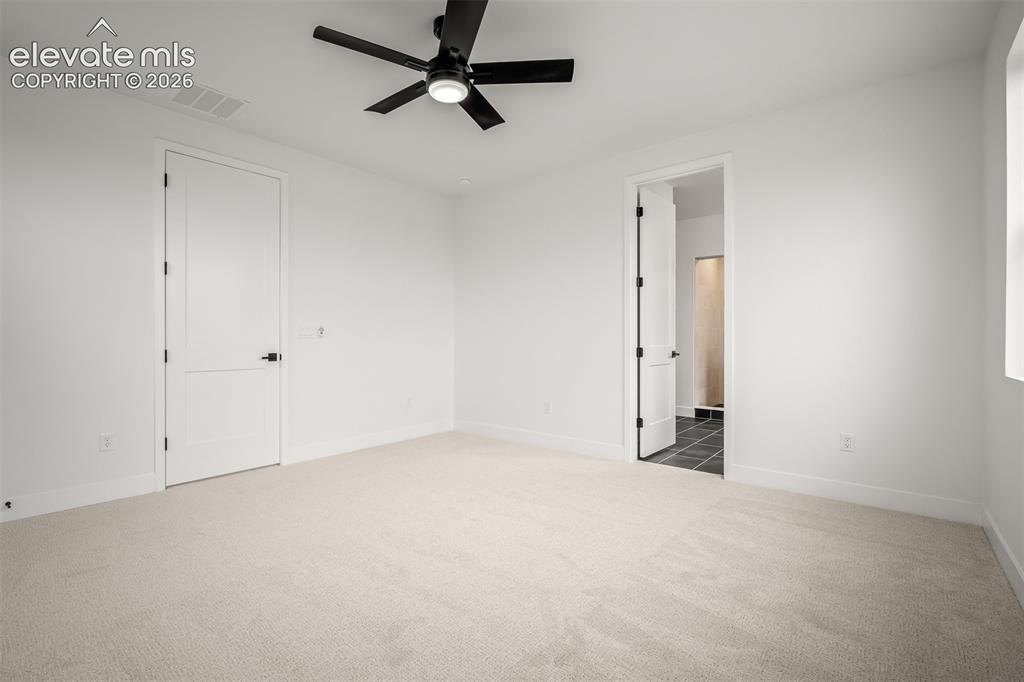 Image 23 of 45: Spacious primary bedroom featuring multiple windows, light-toned carpeting,