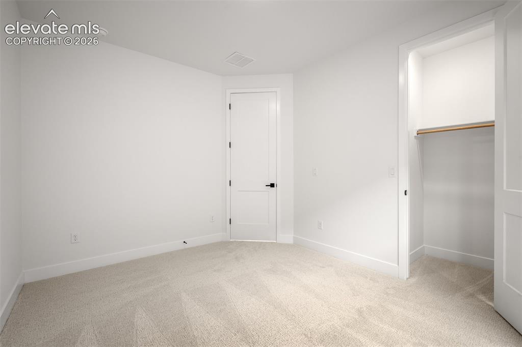 Image 30 of 45: Second bedroom with light-toned carpeted room featuring a white interior do