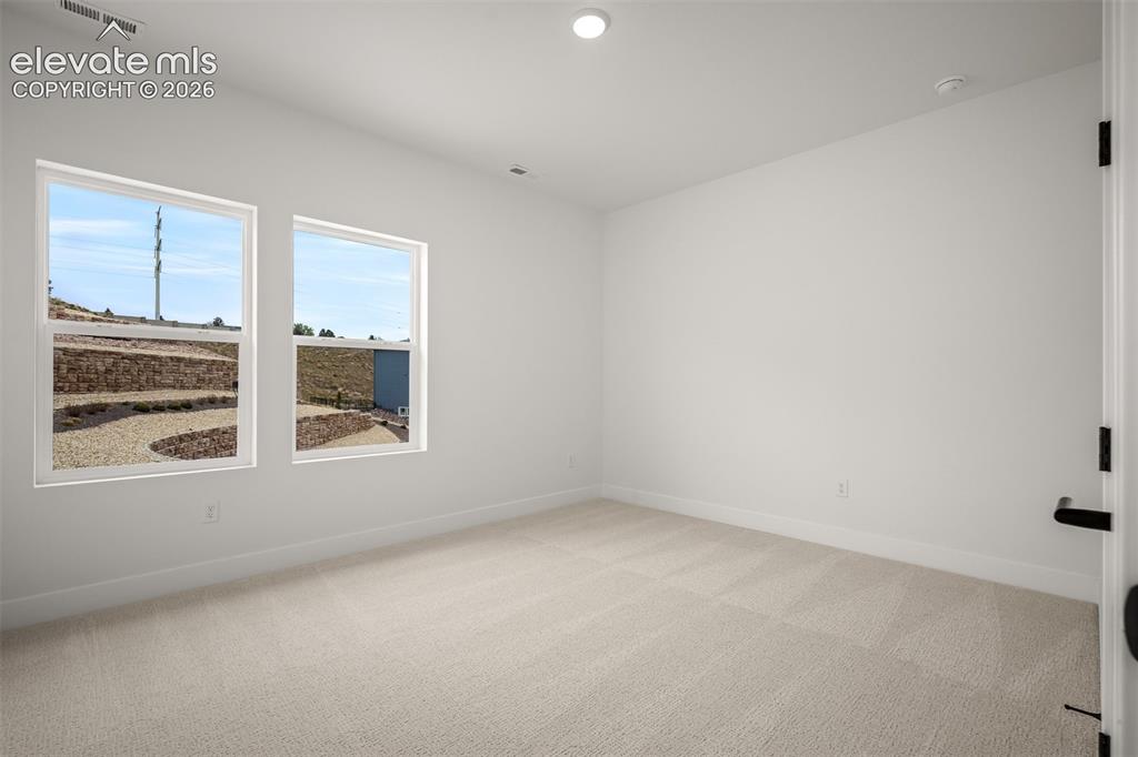 Image 32 of 45: Third bedroom featuring twin windows, neutral wall tones, recessed lighting