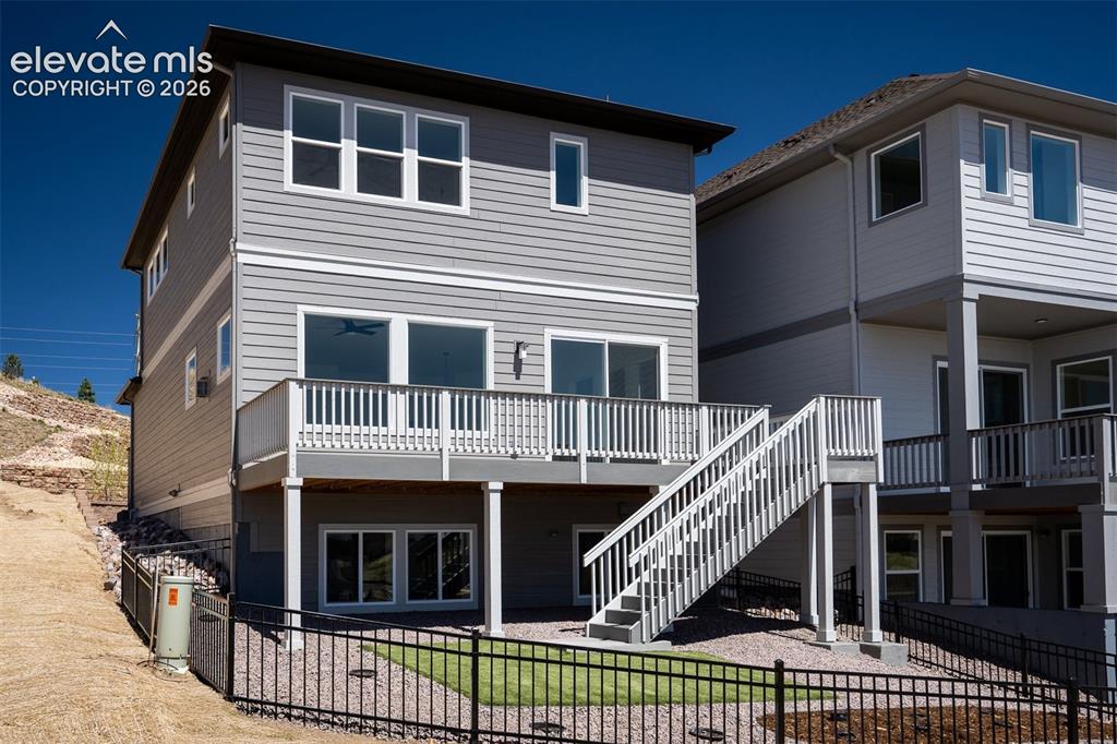 Image 39 of 45: Rear exterior featuring light gray siding with white trim accents and a lar