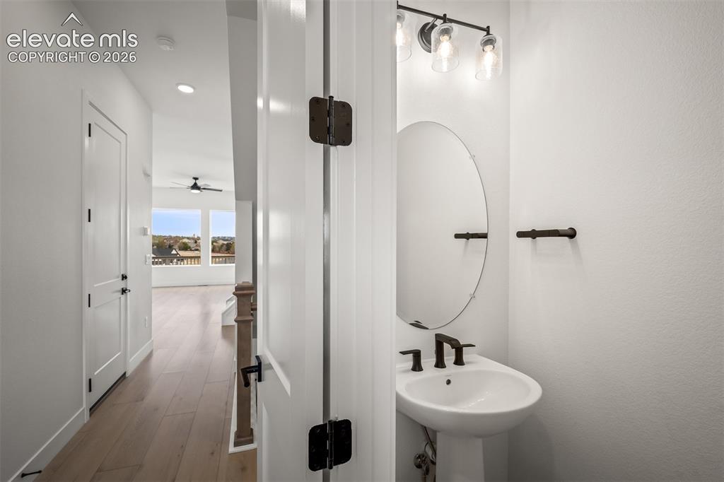 Image 4 of 45: Front Entryway and main level half bathroom with a pedestal sink black fauc