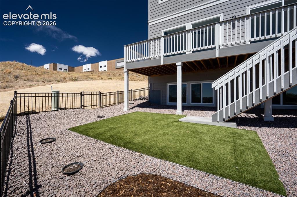 Image 44 of 45: Back yard featuring a synthetic turf lawn area, rock landscaping, and a bla