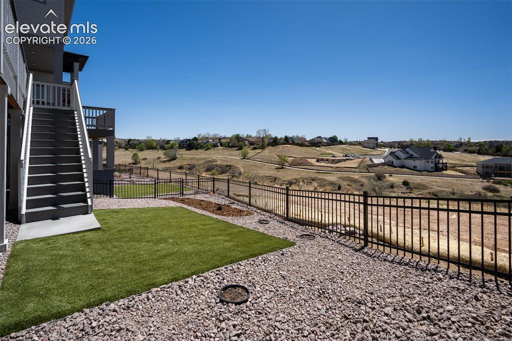 Image 45 of 45: Back yard featuring a synthetic turf lawn area, rock landscaping, and a bla
