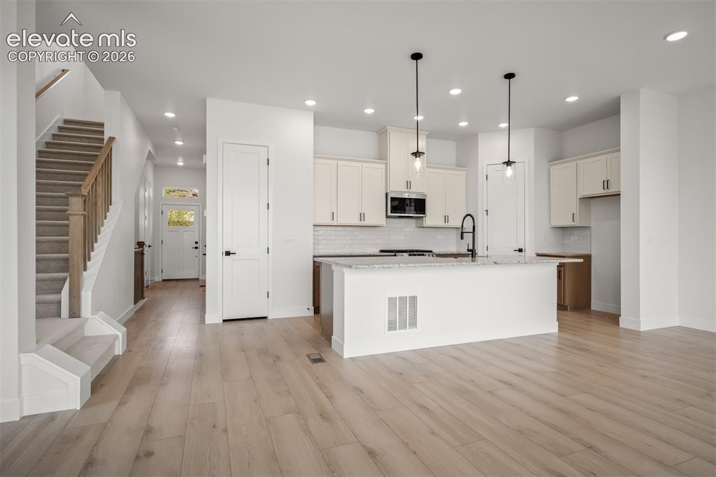 Image 7 of 45: Open-concept living space featuring wood-finish flooring, a contemporary ki