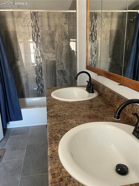 Image 7 of 11: Full bath with tile patterned floors, double vanity, a sink, and shower / b