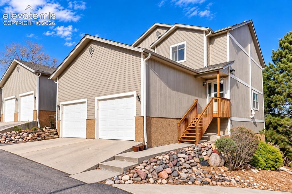 Image 1 of 19: Multi-level exterior with neutral siding, an elevated entry porch, wood ste