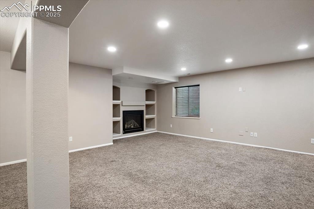 Image 12 of 35: Unfurnished living room with built in features, recessed lighting, carpet f