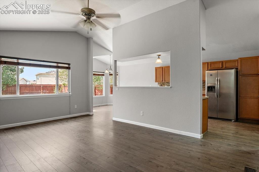 Image 20 of 35: Unfurnished living room featuring lofted ceiling, a ceiling fan, and dark w