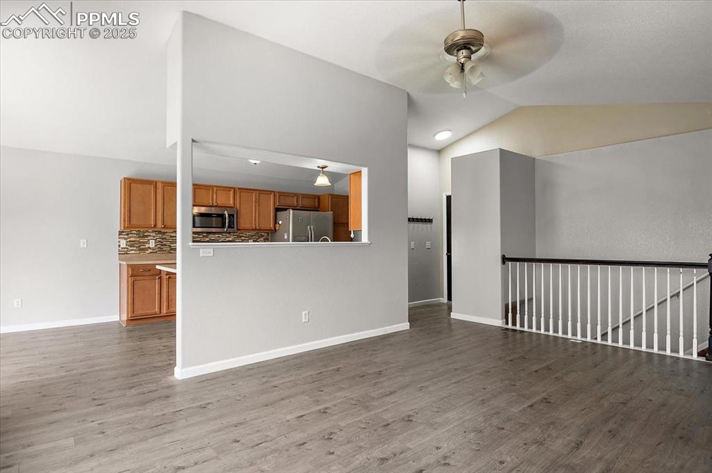 Image 21 of 35: Unfurnished living room featuring a ceiling fan, vaulted ceiling, wood fini