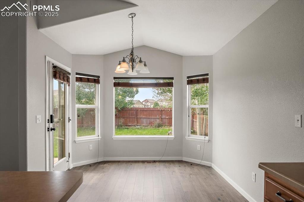 Image 23 of 35: Unfurnished dining area with a chandelier, wood finished floors, lofted cei