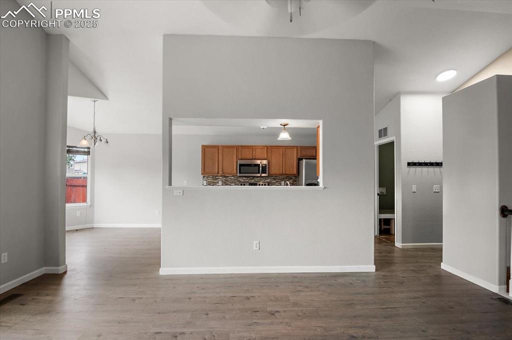 Image 25 of 35: Kitchen featuring brown cabinetry, a chandelier, wood finished floors, loft