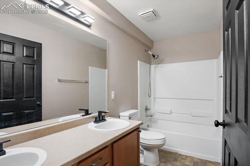 Image 28 of 35: Bathroom featuring double vanity, shower / bathtub combination, stone finis