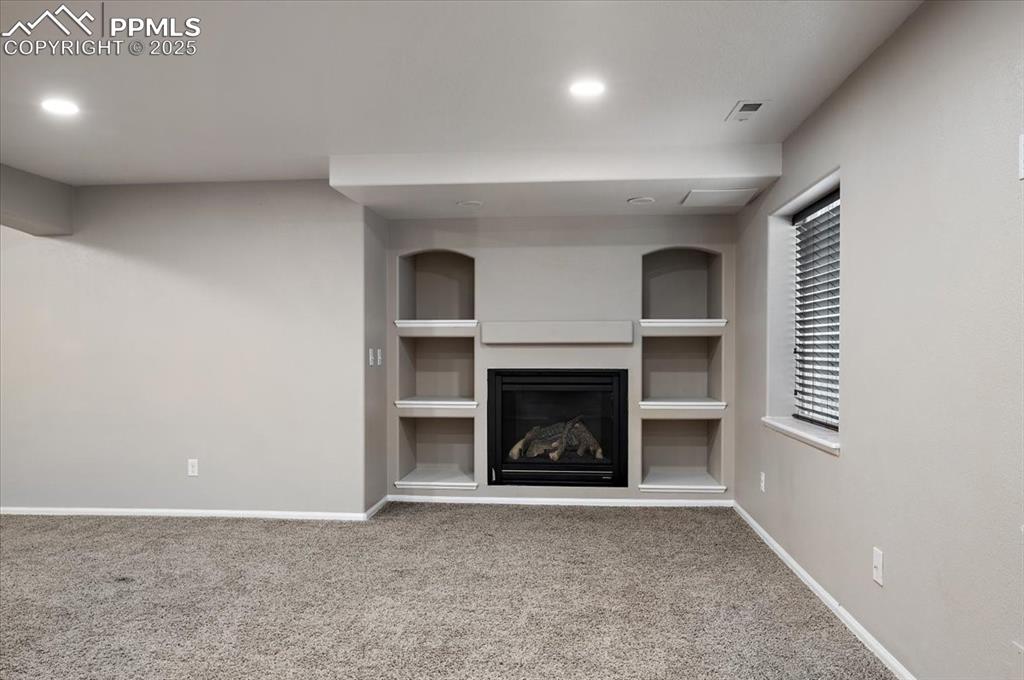 Image 31 of 35: Unfurnished living room with built in features, carpet, recessed lighting, 