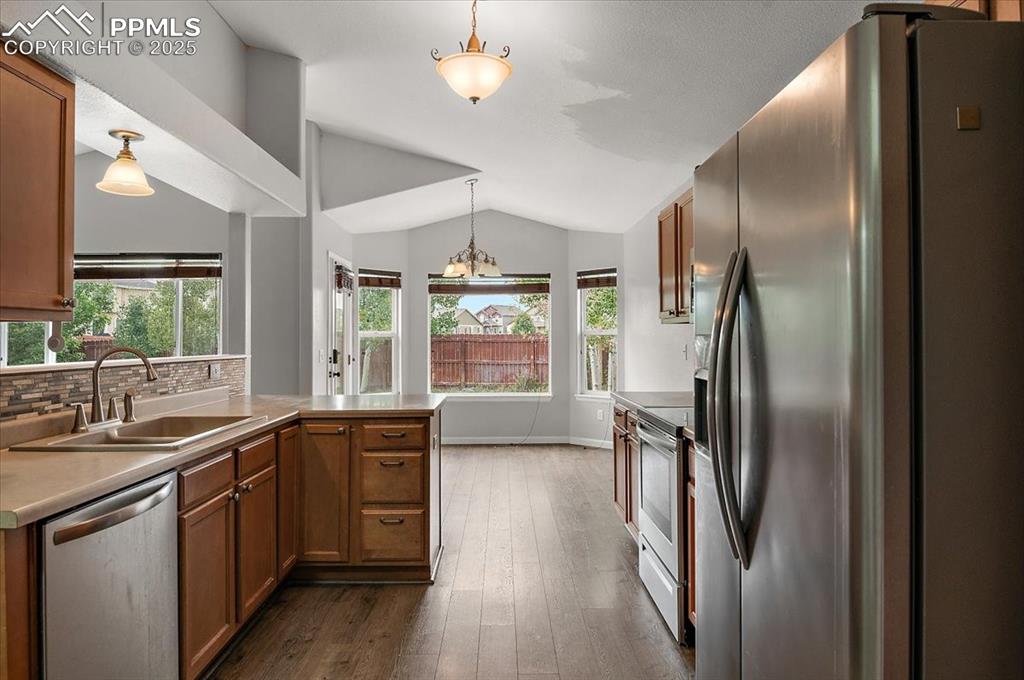 Image 7 of 35: Kitchen with stainless steel appliances, lofted ceiling, dark wood-type flo