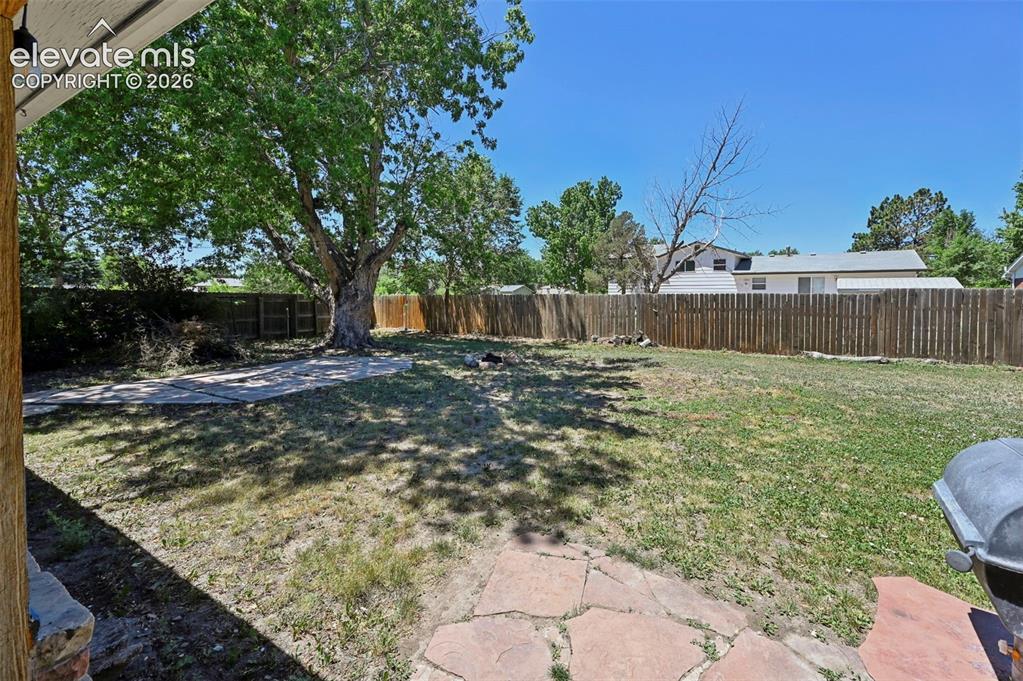 Image 18 of 29: Expansive backyard featuring flagstone patio areas, a mature shade tree, a