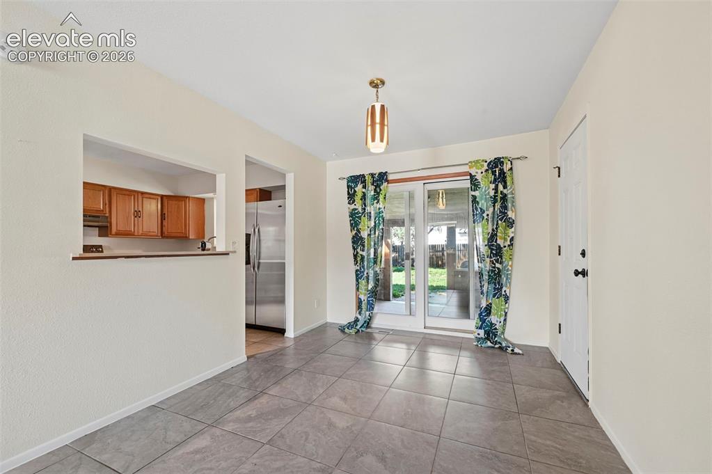 Image 20 of 28: Tiled flooring, overhead lighting, and a pass-through window to the kitchen