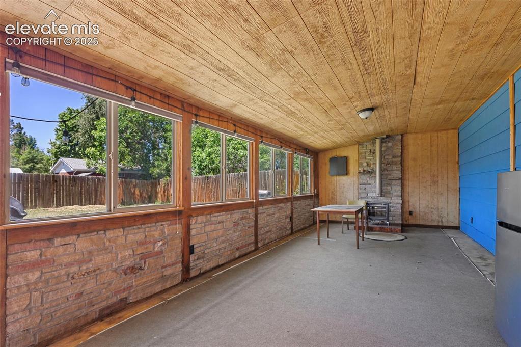 Image 4 of 29: Enclosed patio featuring a wood-finish plank ceiling, stone-look lower wall