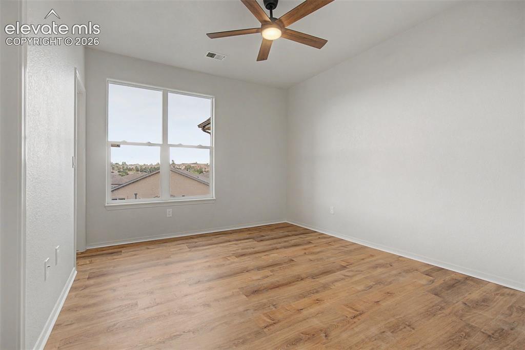 Image 10 of 23: Front bedroom featuring a large window with white trim, new ceiling fan wit