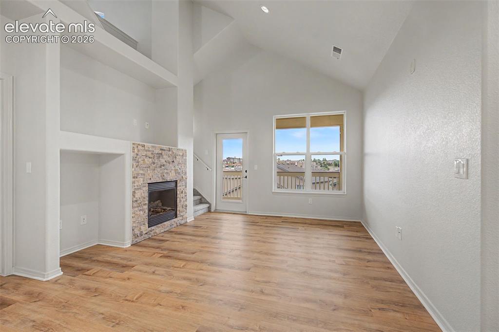 Image 14 of 23: Vaulted ceilings complement the wood-finish flooring and a stone-clad firep