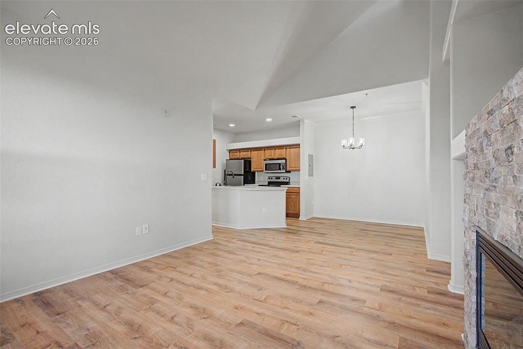 Image 15 of 23: Open concept living area with wood-finish flooring, a stone-clad fireplace 